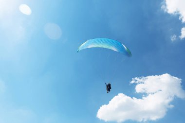 Mavi Paraglider güneşli bir günde bulutlarla gökyüzüne uçuyor..