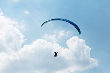 Mavi Paraglider güneşli bir günde bulutlarla gökyüzüne uçuyor..