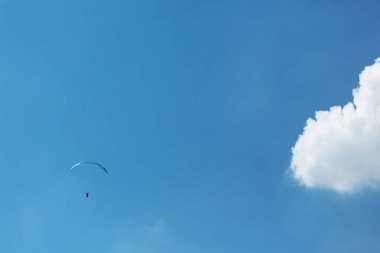 Mavi Paraglider güneşli bir günde bulutlarla gökyüzüne uçuyor..