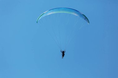 Mavi Paraglider güneşli bir günde bulutlarla gökyüzüne uçuyor..