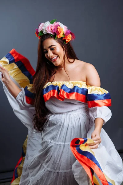 Gri arka planda yalnız dans eden güzel Kolombiyalı bir kadının moda portresi.