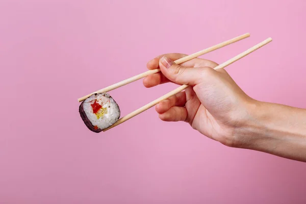 Sabroso maki rollo de sushi con palillos de madera sobre fondo rosa de cerca. Lugar para el título y el texto —  Fotos de Stock