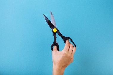 Makas tutan kadın eli. Mavi üzerine izole edilmiş..