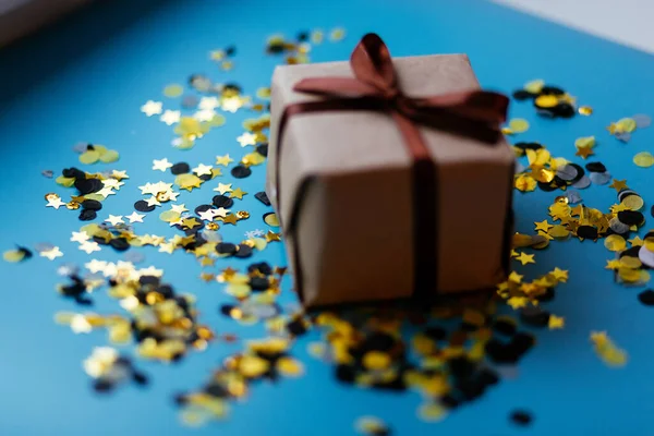 礼物盒 蓝色背景上有手工褐色弓形 黄色黑色圆饼 平铺风格 圣诞节和新年的概念 — 图库照片