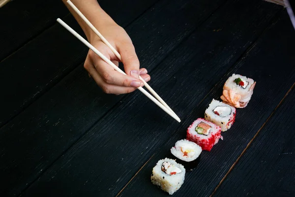 Mão Feminina Leva Rolos Sushi Com Pauzinhos Chineses Deitado Numa — Fotografia de Stock