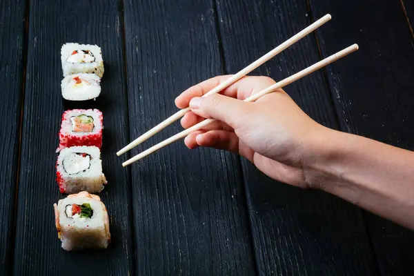 Vrouwelijke Hand Neemt Stokjes Sushi Broodjes Met Chinese Eetstokjes Liggend — Stockfoto