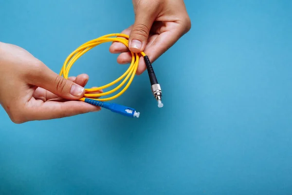 Las manos de las mujeres sostienen SC y FC conector cable de conexión de fibra óptica monomodo sobre fondo azul — Foto de Stock