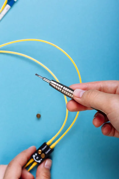 Women Handholds un destornillador para afinar el atenuador óptico. Enfoque selectivo. Fondo azul — Foto de Stock