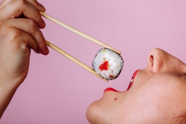 Dudakların makroyu suşi rulosuyla kapat. Japon yemeği yiyen kadın.