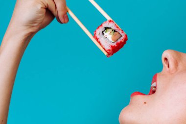 Dudakların makroyu suşi rulosuyla kapat. Japon yemeği yiyen kadın..
