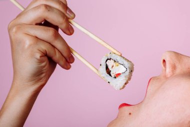 Dudakların makroyu suşi rulosuyla kapat. Japon yemeği yiyen kadın..
