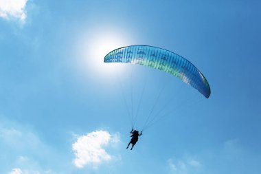 Mavi Paraglider güneşli bir günde bulutlarla gökyüzüne uçuyor..