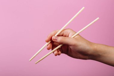 Öğretim: yemek çubuklarını yemek çubuklarıyla nasıl tutulacağını. Pembe arka planda izole edilmiş. Adım 4.