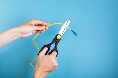 Optik fiberi makasla yok et. Mavi üzerine izole edilmiş..