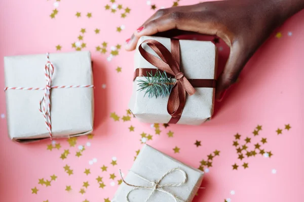 手里拿着礼品盒的非洲女人的手 礼品盒上有一个用星星和雪花做成的彩色背景的蝴蝶结 有选择的重点 — 图库照片