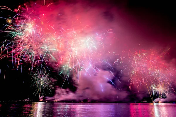 Suyun üstünde kara gökyüzü arka planında yansıması olan bayram havai fişekleri.