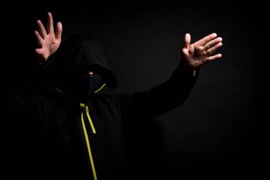 Maskeli hırsız siyah arka planda izole edilmiş kollarıyla seni korkutmaya çalışıyor..