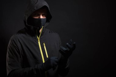 Maskeli adam eldiven takıyor. Soygun ya da hackleme hazırlığı.