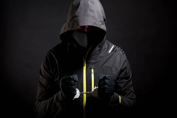 Bilinmeyen, ayırt edilemez bir haydut ya da kelepçeli ve siyah giysili Hucker tutuklandı. Kriz nedeniyle suç kavramı siyah arka planda izole edilmiş..