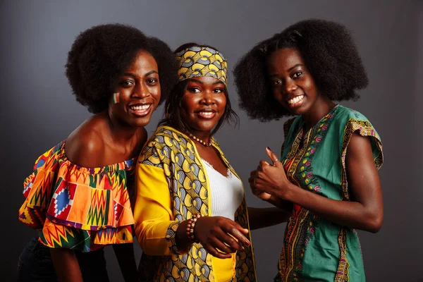 Üç güzel Afrikalı model geleneksel kıyafetlerle eğleniyor ve gülüyor. Kongo Cumhuriyeti, Fildişi Sahili ve Zimbabwe kadınları.