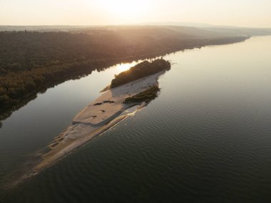 Gün batımında yemyeşil ormanlarla çevrili sakin bir nehir adasının havadan görüntüsü. g.