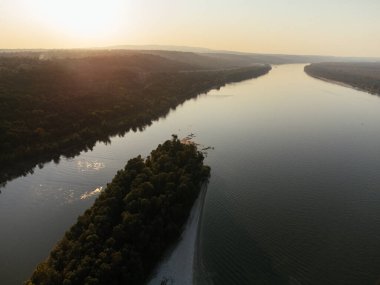 Gün batımında yemyeşil ormanlarla çevrili sakin bir nehir adasının havadan görüntüsü. g.