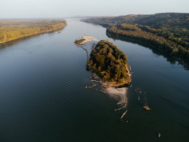 Gün batımında yemyeşil ormanlarla çevrili sakin bir nehir adasının havadan görüntüsü. g.