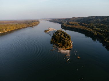 Gün batımında yemyeşil ormanlarla çevrili sakin bir nehir adasının havadan görüntüsü. g.
