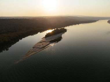 Gün batımında yemyeşil ormanlarla çevrili sakin bir nehir adasının havadan görüntüsü. g.
