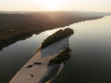 Gün batımında yemyeşil ormanlarla çevrili sakin bir nehir adasının havadan görüntüsü. g.