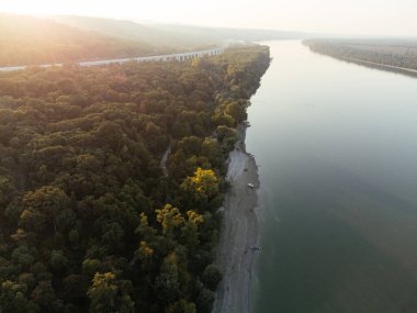 Gün batımında yemyeşil ormanlarla çevrili sakin bir nehir adasının havadan görüntüsü. g.