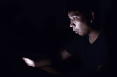 Akıllı telefon siyah karanlık odada kullanarak ve bir şey düşünüyorum Asya adam