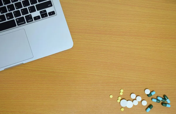 simple top view of computer with medicine drug pills and tablet on wooden background