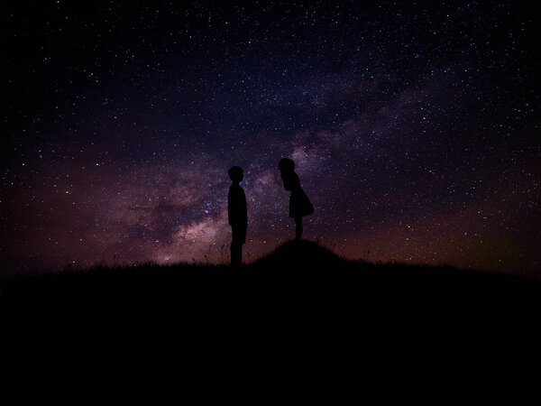 Silhouette of man and woman over grass and hill with star milky way backgrounds, romantic valentine