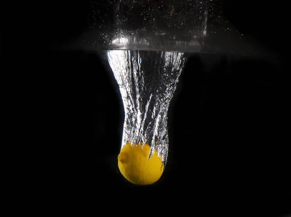 siyah arka plan üzerine su sıçramasına içine düşen sarı limon