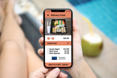 Havuzun yanında ekranda telefon app teslim suşi yemek ile tutan kadın