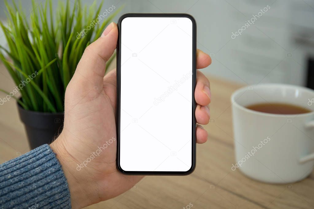 Male hand holding black touch phone with isolated screen in room
