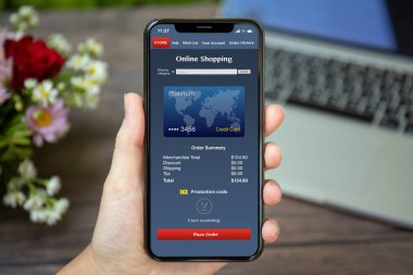 app online ekranda Danışma dizüstü bilgisayar ve çiçekler üzerinde alışveriş ile telefon tutarak el