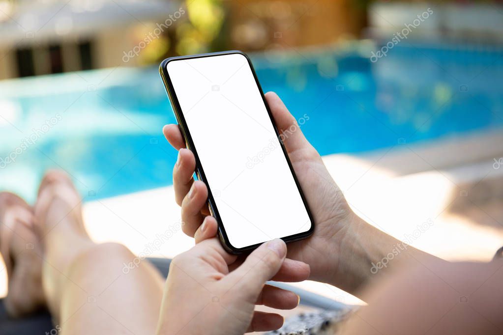 woman by the pool holding phone with an isolated screen