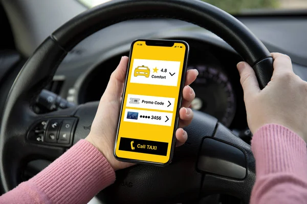 women hands holding phone with app call taxi on screen in the car