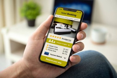 adam el üstünde perde evin odasında telefon app otel rezervasyonu ile tutarak