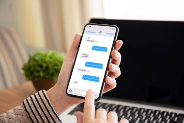 tablonun üst kısmındaki ofiste dizüstü bilgisayar ile ekranda dokunmatik telefon app messenger ile tutarak el