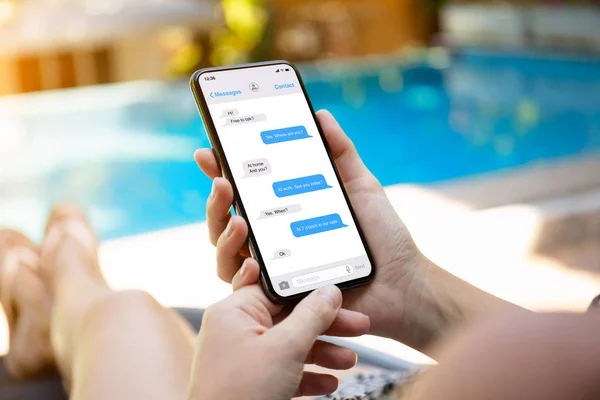 妇女在游泳池边拿着手机与应用程序信使在屏幕上 — 图库照片
