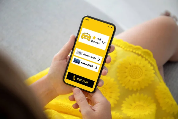 女性手在黄色礼服拿着手机与应用程序叫出租车在屏幕上 — 图库照片