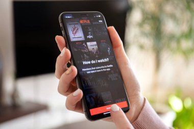 Anapa, Rusya - 20 Şubat 2019: iphone X çokuluslu eğlence şirketi Netflix ile akış medya ve video üstünde belgili tanımlık perde sağlar tutan kadın.