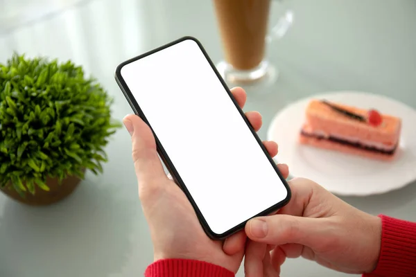 Женская рука держит телефон с изолированным экраном в кафе — стоковое фото