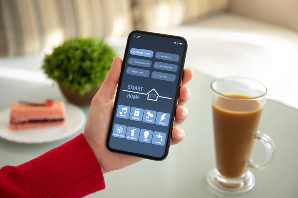Жіноча рука тримає телефон з додатком розумний будинок на екрані — стокове фото