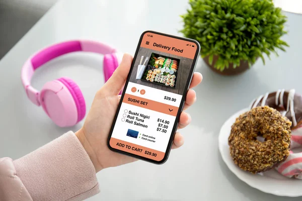 Female hands holding phone with app delivery food on screen — Stock Photo, Image