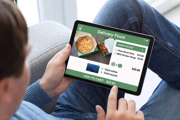 Muž v džínách drží tabletový počítač s aplikací dodávky potravin — Stock fotografie