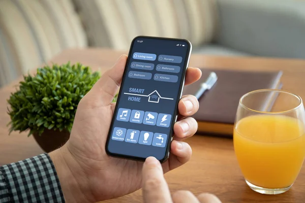 Чоловічої руки, тримаючи телефон з app смарт-вдома на екрані — стокове фото